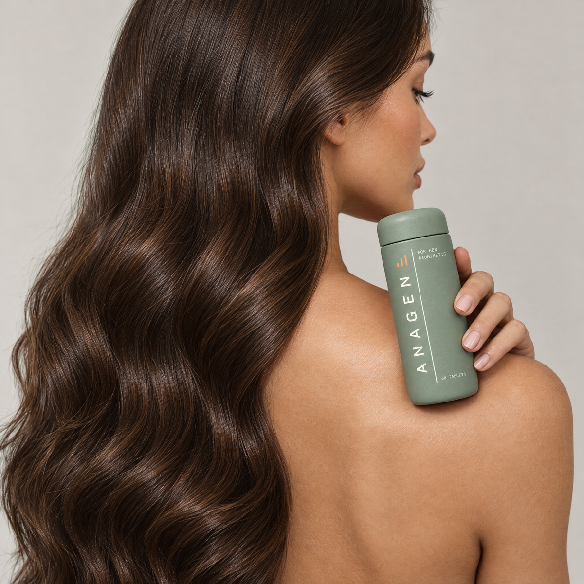Woman with long glossy brown hair holding Anagen for Her at her shoulder