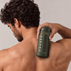 Man with thick curly hair holding Anagen for Him over his shoulder