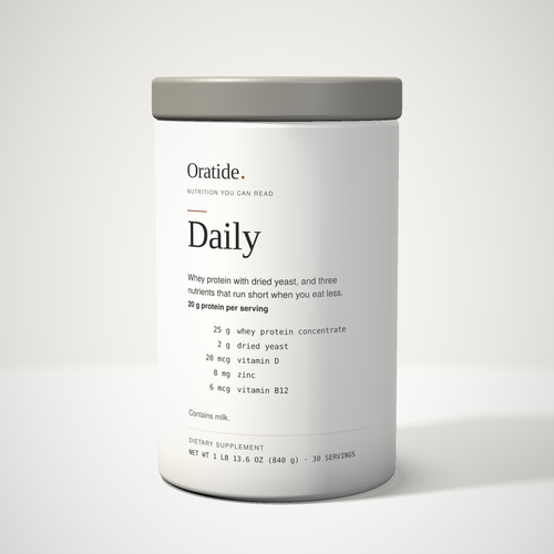 Oratide Daily, a cream 840 g canister with a grey lid, turned slightly and lit from the left on a pale surface.