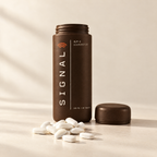 A bottle of Oratide Signal with its cap off and white oblong tablets beside it