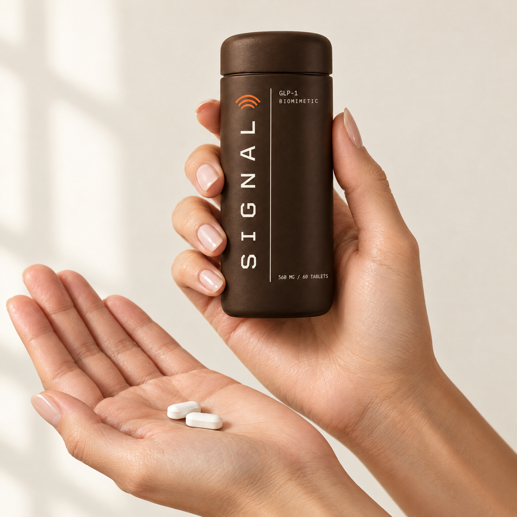 Two white oblong Signal tablets in an open palm, the bottle held in the other hand